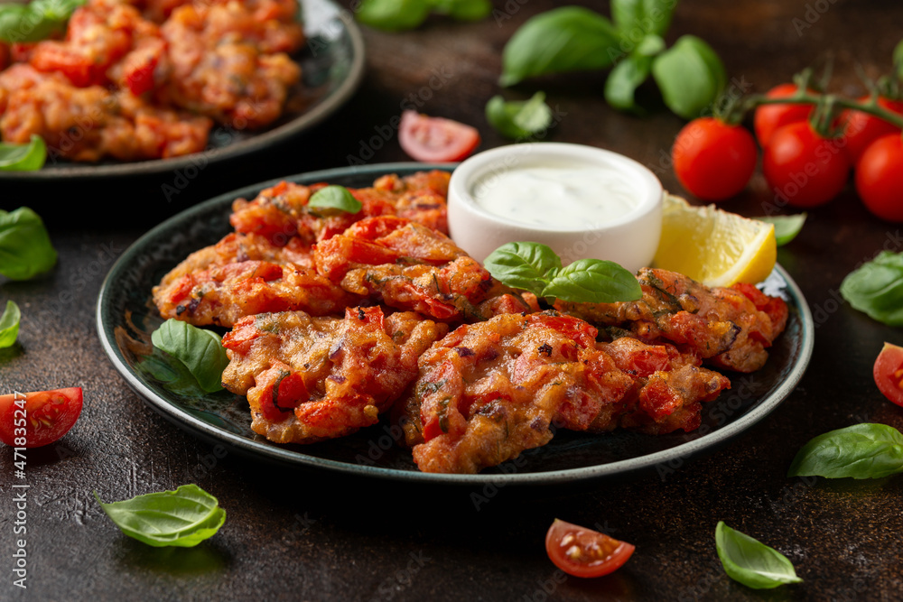 Greek tomato fritters, tomatokeftedes served with yogurt on plate. Greek tomato fritters, tomatokeftedes served with yogurt on plate.