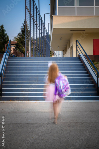 Obraz na plátně Schoolgirl with a backpack disappearing while walking to the stairs