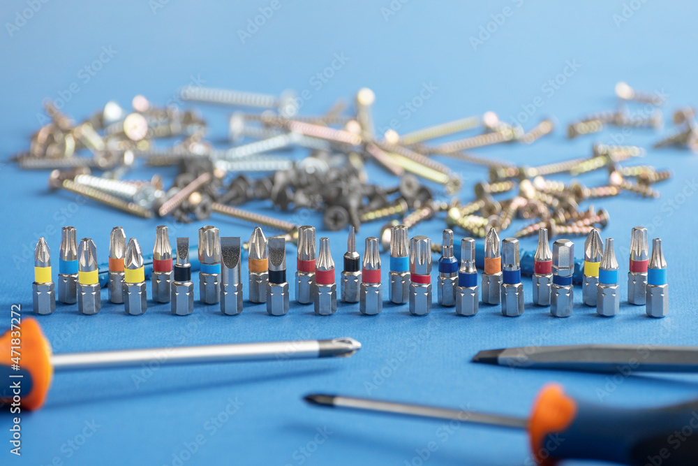 Screwdriver bits and fasteners of various kinds on a blue background. Copy space.