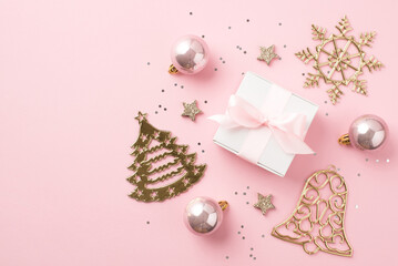 Top view photo of pink christmas decorations balls glowing stars sequins gold bell pine snowflake shaped ornaments and white giftbox with pink bow on isolated pastel pink background with copyspace
