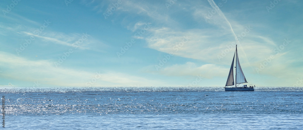 Obraz premium Small sailboat sailing through a silver sea in a sunny day