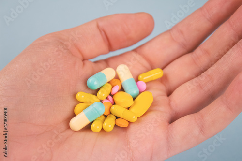 Man's hand holding assorted multicolored medicine pills, capsules and tablets. A handful of pills. Immune system vitamins and supplemets. Dietary bio supplements