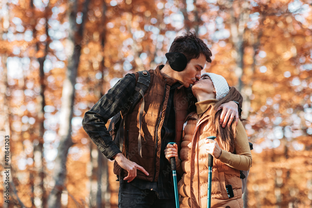 Young couple hiking in the woods, kissing. Autumn vibes