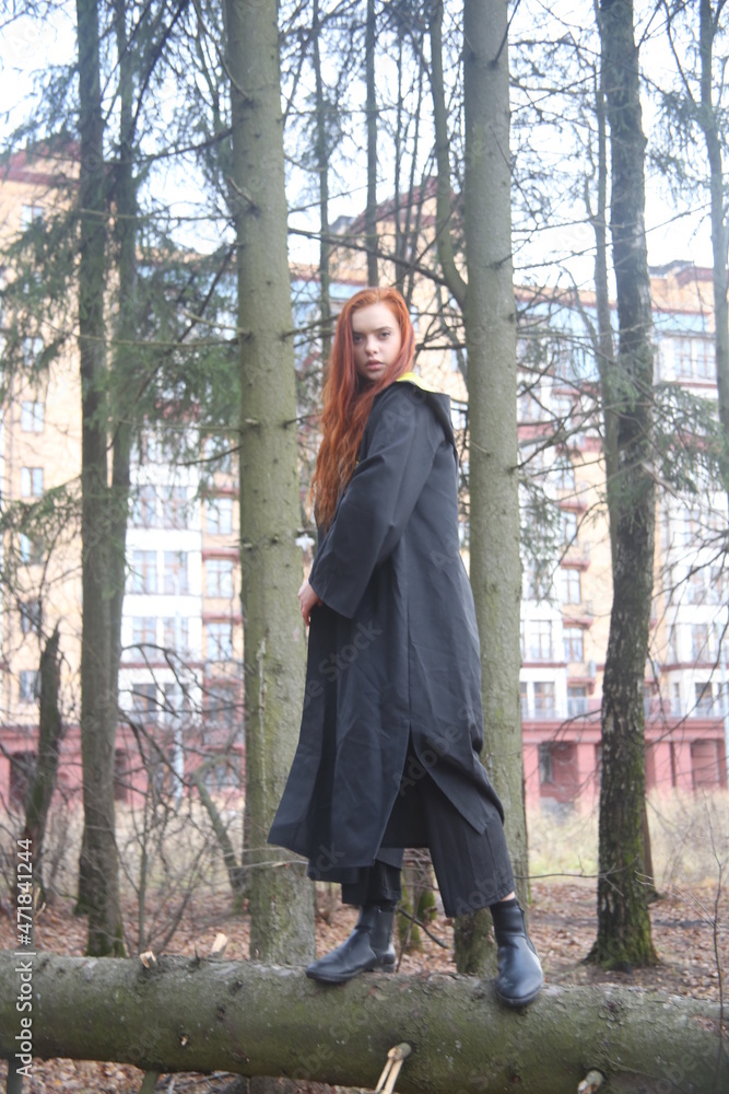 Closeup portrait of a young woman with red hair in a forest girl female beauty cute face lady pretty woman lifestyle black raincoat one person model Closeup portrait of a young woman with red hair in a forest girl female beauty cute face lady pretty woman lifestyle black raincoat one person model