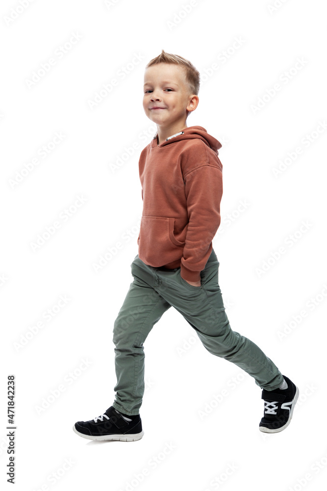 The smiling boy is walking. Preschooler in gray jeans and a brown sweater. Positiveness and movement. Isolated on white background. Vertical. The smiling boy is walking. Preschooler in gray jeans and a brown sweater. Positiveness and movement. Isolated on white background. Vertical.