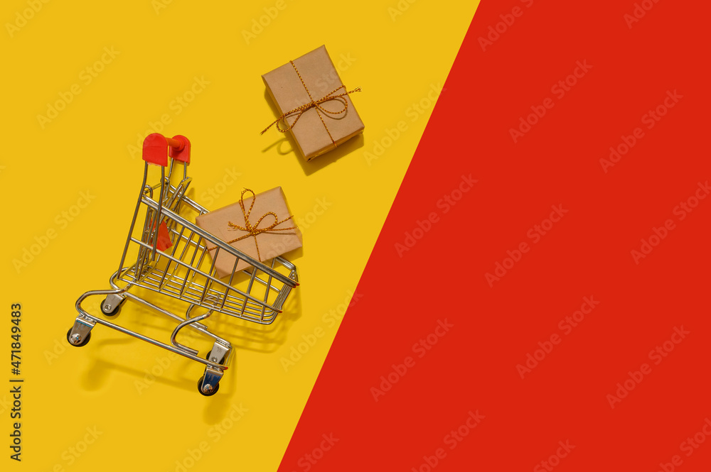 Online sales mini basket with gifts on a yellow and red paper background.