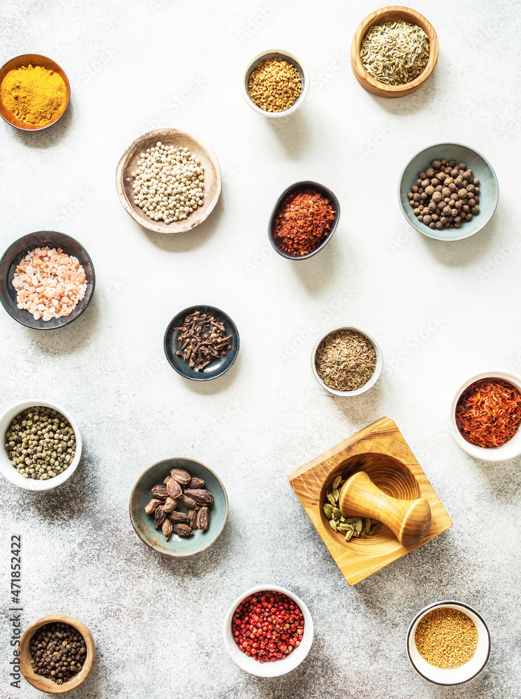 Various dry spices in small bowls and mortar flat lay on grey background. Various dry spices in small bowls and mortar flat lay on grey background.