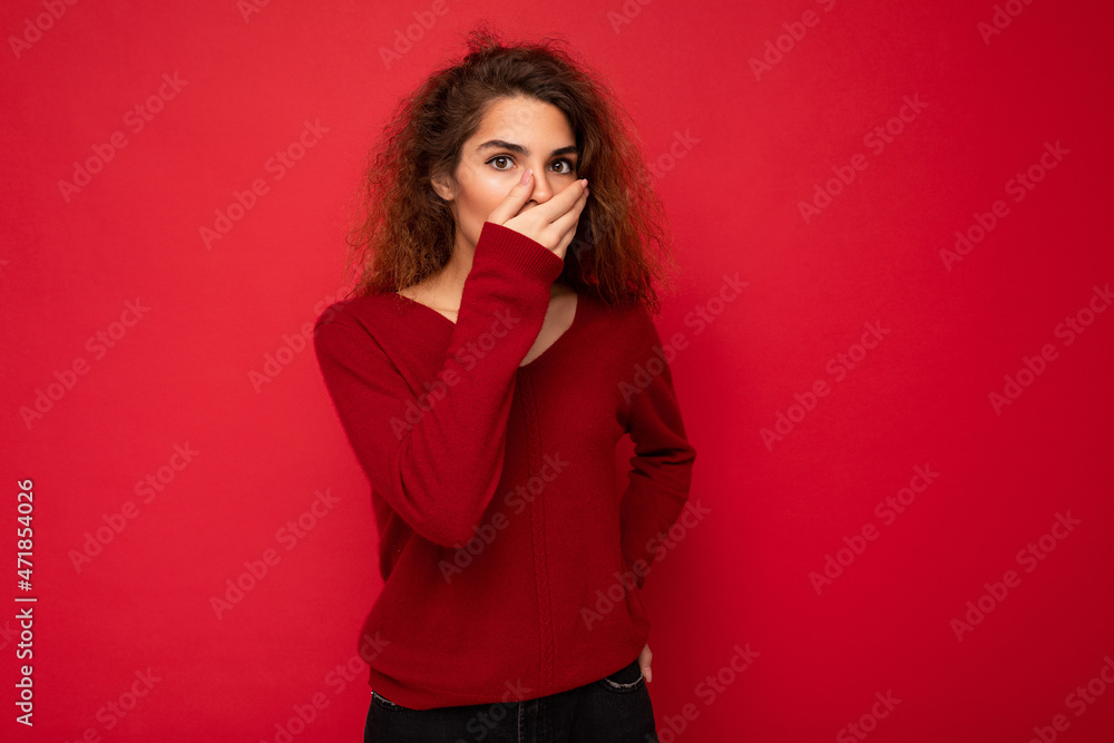 Photo of young shocked amazed attractive brunette curly woman with sincere emotions wearing casual red sweater isolated on red background with copy space Photo of young shocked amazed attractive brunette curly woman with sincere emotions wearing casual red sweater isolated on red background with copy space