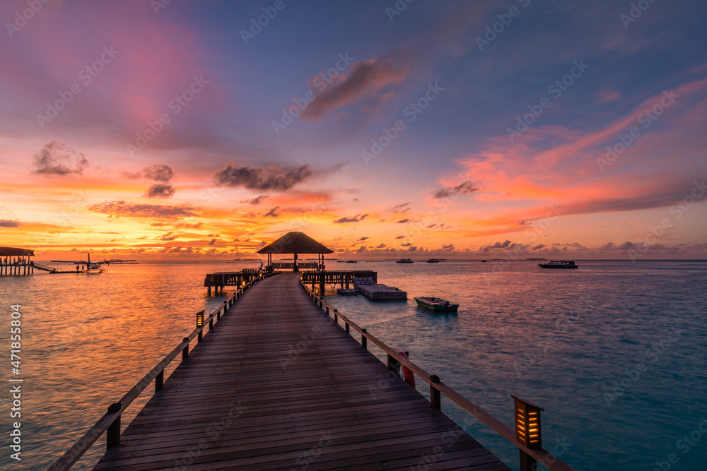 Fototapeta premium Amazing sunset panorama at Maldives. Luxury resort villas seascape with soft led lights under colorful sky. Beautiful twilight sky and colorful clouds. Beautiful beach background for vacation holiday 