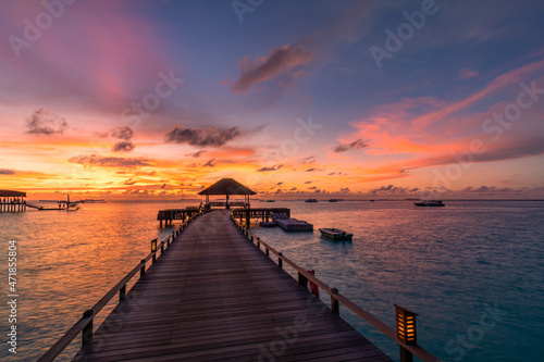 Amazing sunset panorama at Maldives. Luxury resort villas seascape with soft led lights under colorful sky. Beautiful twilight sky and colorful clouds. Beautiful beach background for vacation holiday © icemanphotos