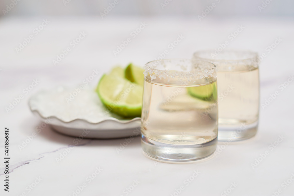 Shot of tequila with lime and salt on white background Shot of tequila with lime and salt on white background