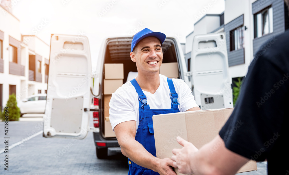 Removal company worker unloading boxes from minibus into customer's home