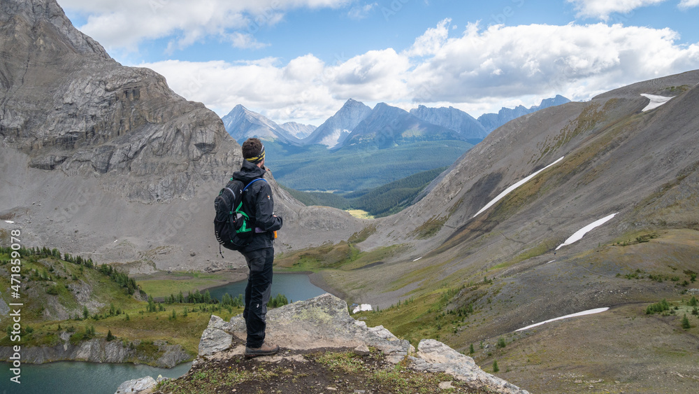 Male hiker overlooking alpine valley from top of the mountain, Canadian Rockies, Canada