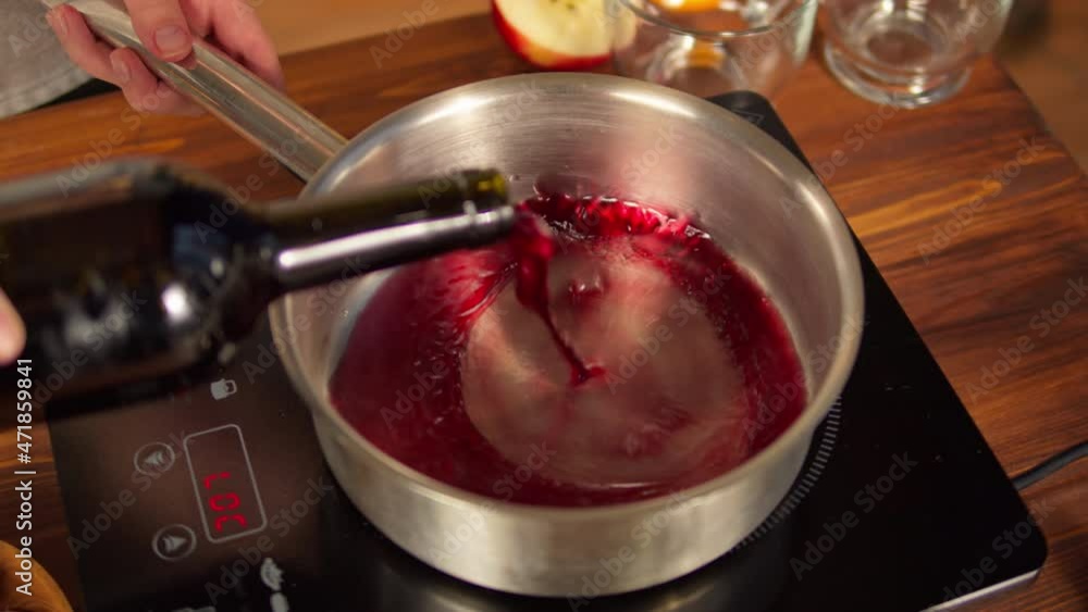 Woman cooking mulled wine, gluhwein with apples and oranges recipe. Pouring red wine close-up. Winter traditional drinks. Christmas holidays and new year time. Woman cooking mulled wine, gluhwein with apples and oranges recipe. Pouring red wine close-up. Winter traditional drinks. Christmas holidays and new year time.