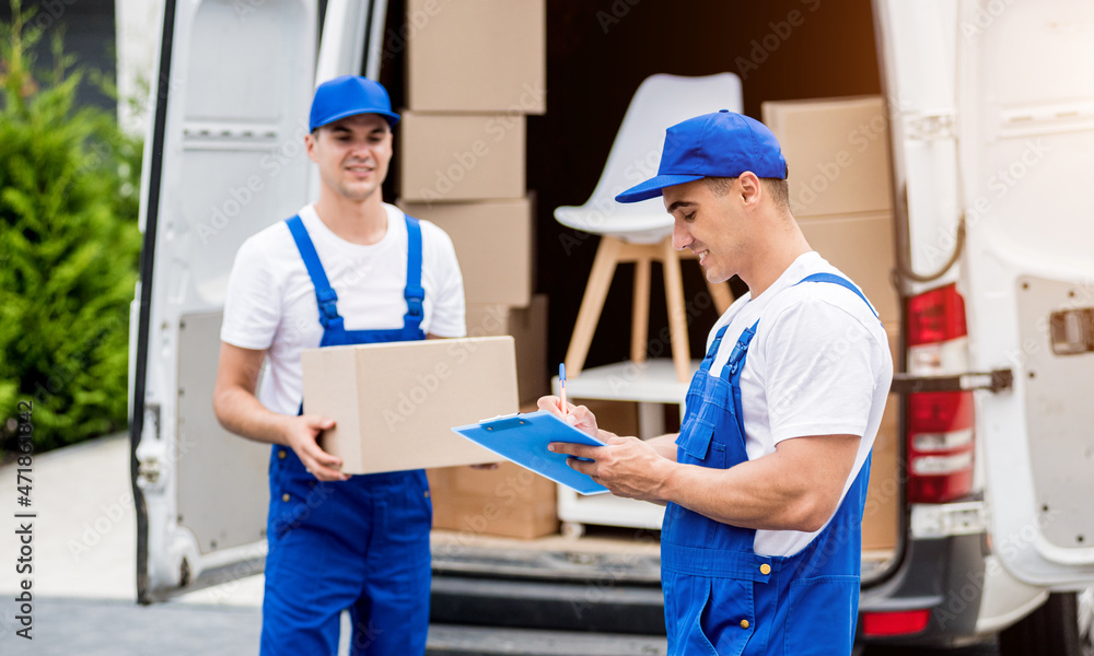 Two removal company workers unloading boxes from minibus into new home Two removal company workers unloading boxes from minibus into new home
