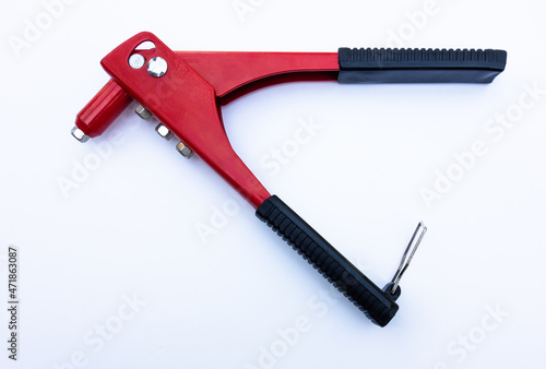 Red metal tool for tightening rivets on white isolate. The riveter is manual. The production tool is red.
