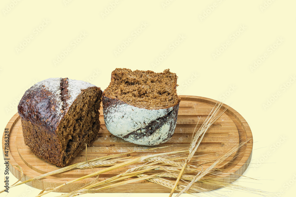 View of cut dark loaf bread and spikelets of rye on a cutting board isolated. Sweden. View of cut dark loaf bread and spikelets of rye on a cutting board isolated. Sweden.
