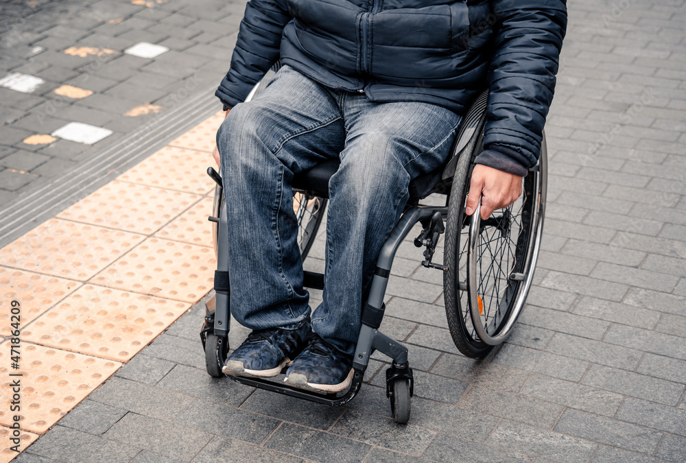 Obraz premium Person with a physical disability waiting for city transport with an accessible ramp.