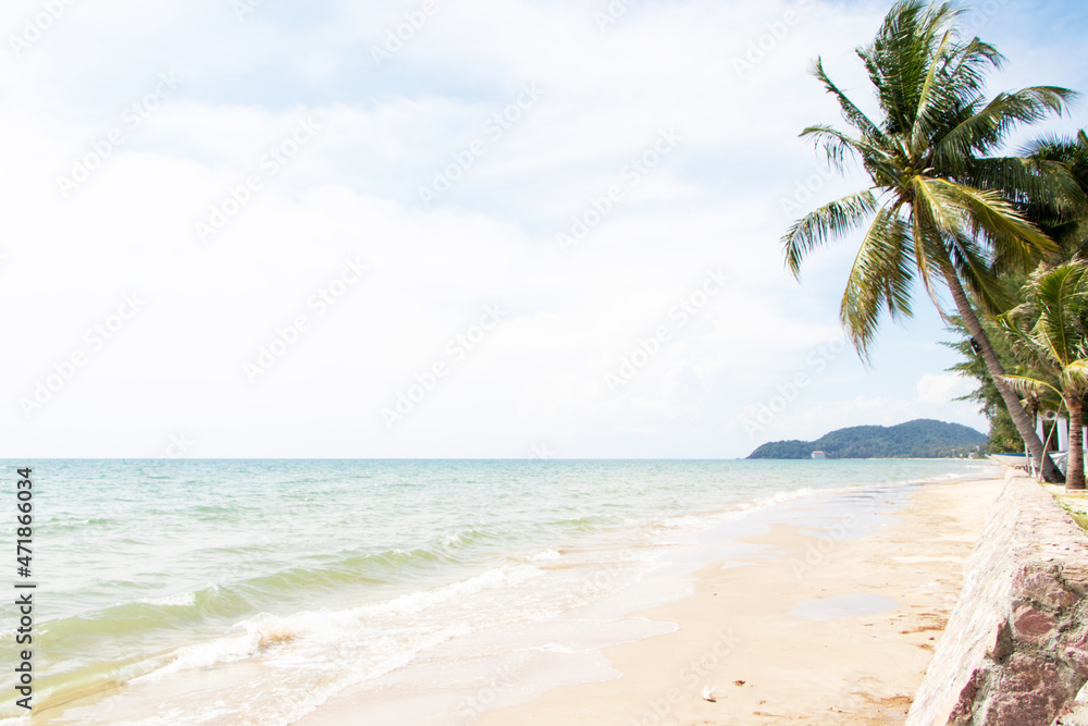 Beautiful tropical beach with blue sky, white clouds abstract texture background. Looking into distance, you can see mountains close to sea at end of horizon. Summer vacation, holiday travel concept.