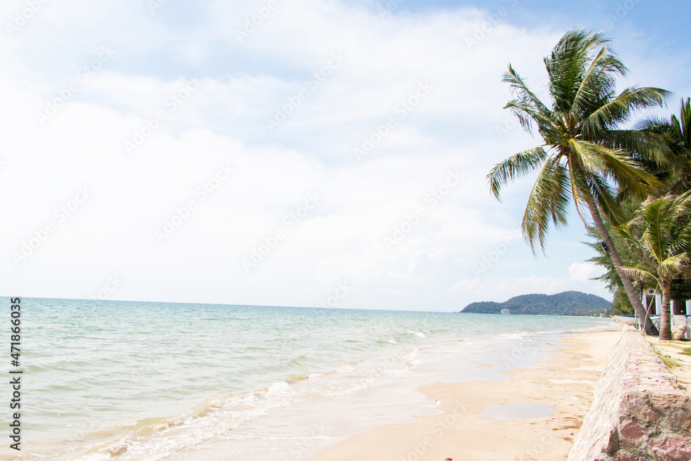 Obraz premium Beautiful tropical beach with blue sky, white clouds abstract texture background. Looking into distance, you can see mountains close to sea at end of horizon. Summer vacation, holiday travel concept.