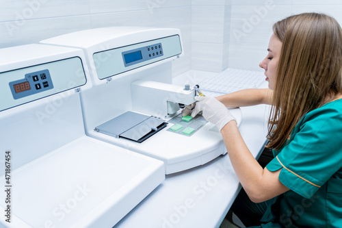 Laboratory assistant works at paraffin wax dispenser tissue embedding machine.