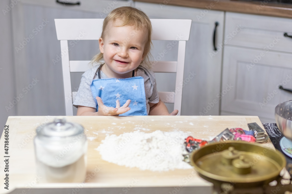 Llittle cute boy is posing at the table ready to bake cookies in the kitchen. Llittle cute boy is posing at the table ready to bake cookies in the kitchen.