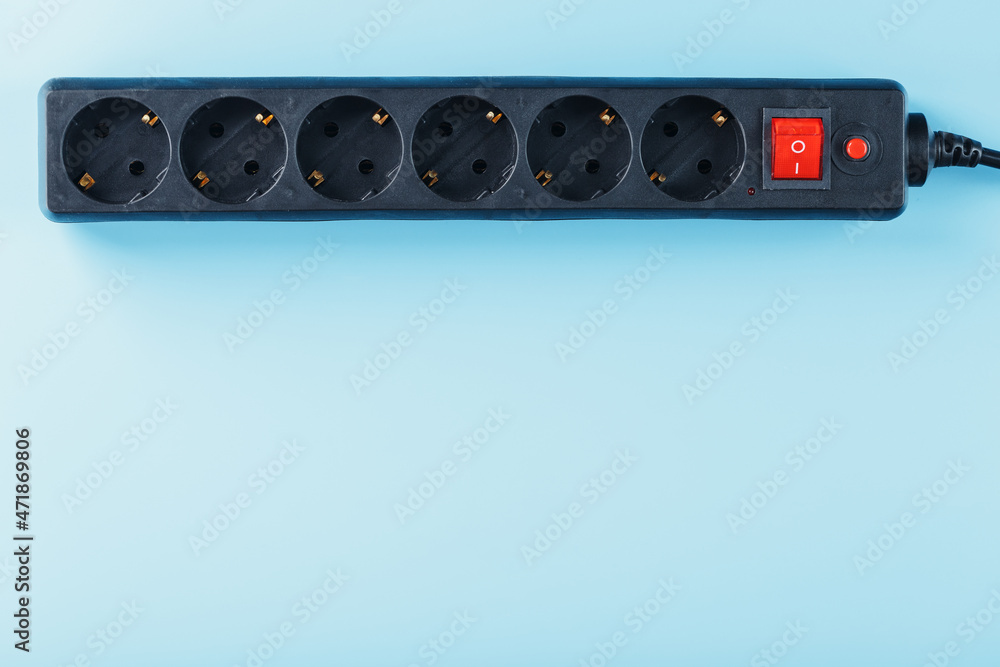A black surge protector with portable sockets and a red button on a blue background. A black surge protector with portable sockets and a red button on a blue background.