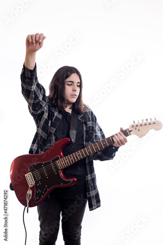 Vertical image of teenager raising his fist while playing electric guitar on white background.