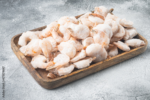 Boiled and frozen shrimps, on wooden tray, on gray background, with copy space for text