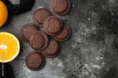 Jaffa Cakes. Cookies covered with dark chocolate and filled with orange marmalade, on black dark stone table background, top view flat lay, with copy space for text