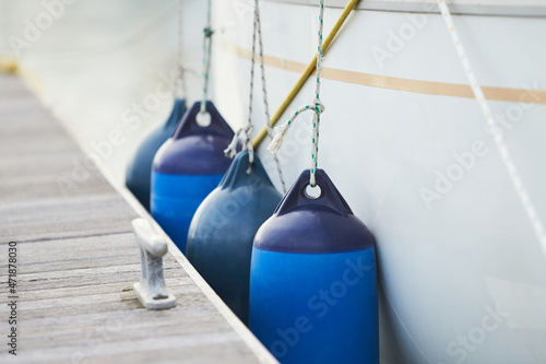 Fotografia White fenders suspended between a boat and dockside for protection