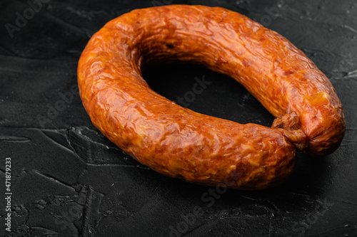 Pork dry cured meat sausage, on black dark stone table background, with copy space for text