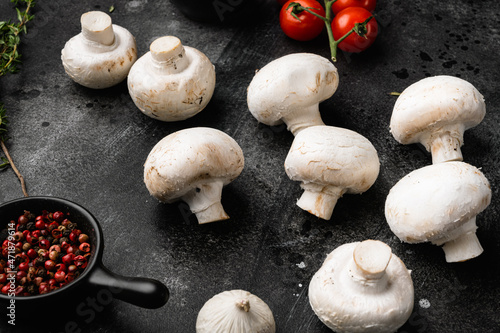 Fresh white champignon mushrooms, on black dark stone table background
