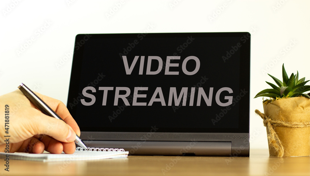 Video streaming symbol. Tablet with concept words Video streaming. Businessman hand with pen, house plant. Copy space. Beautiful white background. Business, video streaming concept, copy space. Video streaming symbol. Tablet with concept words Video streaming. Businessman hand with pen, house plant. Copy space. Beautiful white background. Business, video streaming concept, copy space.
