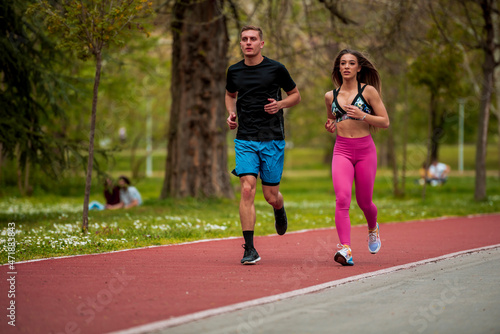Healthy couple jogging together on running track in park