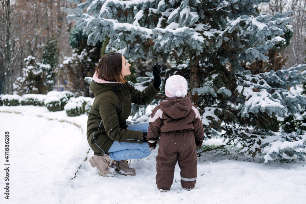 Winter walks with babies and young children. Baby toddler in Winter, How to Protect kids in Cold Weather. Mother and baby girl daughter walking in the winter park