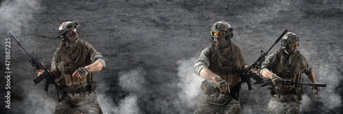 Three mercenary soldiers during a special operation in the smoke against the background of a dark concrete wall - photo with copy space in center. Format photo 3x1. photo