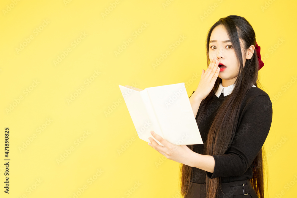 Shocked student. Exam deadline. Study stress. Worried speechless astonished girl teenager holding book isolated on yellow empty space background. Shocked student. Exam deadline. Study stress. Worried speechless astonished girl teenager holding book isolated on yellow empty space background.