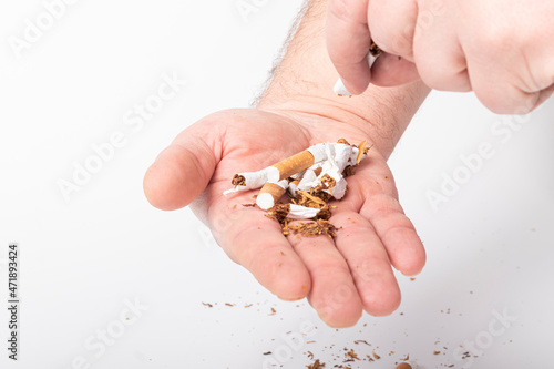 a human hand. the man on her hair. she breaks the cigarettes, and pours them into the other palm. on a white background. close-up