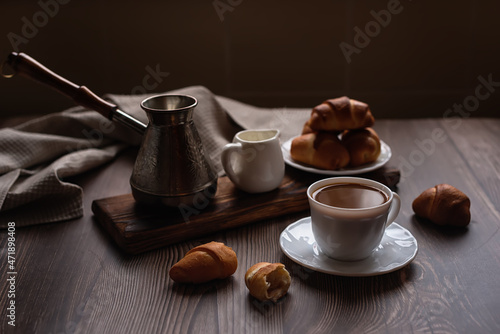 Fototapeta Naklejka Na Ścianę i Meble -  evening relaxation: freshly brewed coffee with cream and croissants on a dark wooden background
