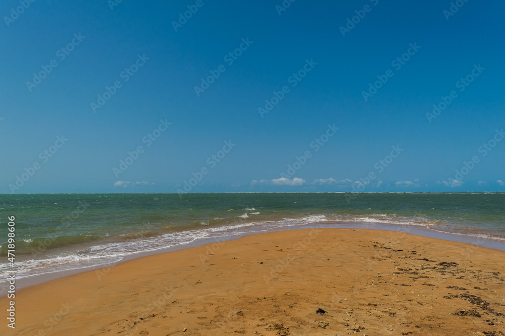 praia deserta com areias escuras e céu azul