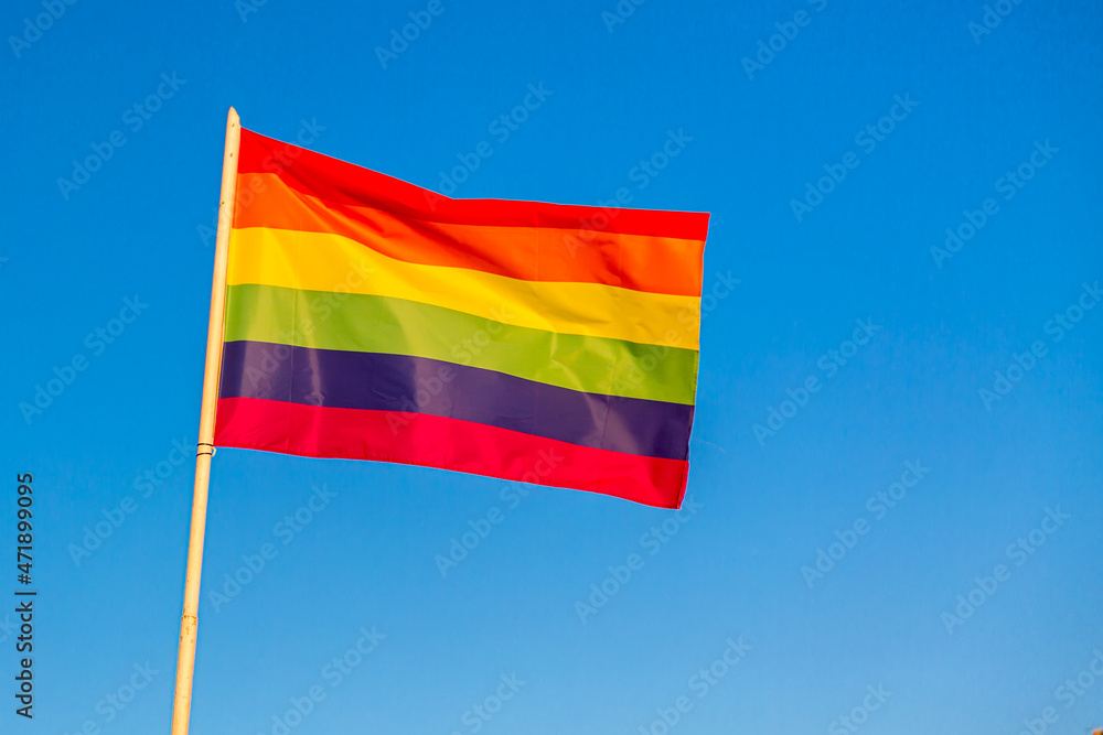 Rainbow flag LGBT movement symbol against blue sky background Rainbow flag LGBT movement symbol against blue sky background