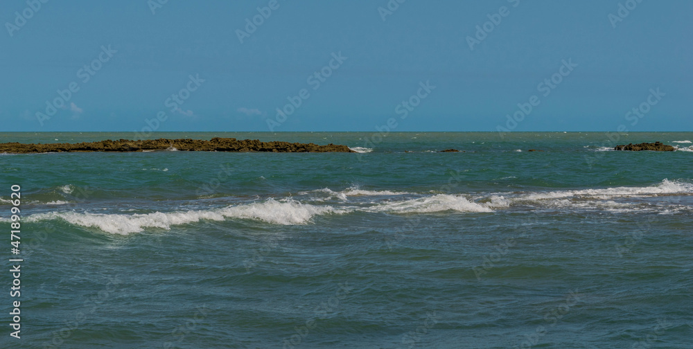 Linda vista de praia com muitas pedras e um céu azul