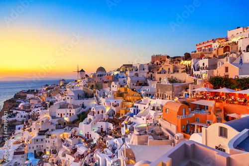 Greece vacation background. Famous iconic Oia village with traditional white houses and windmills during colorful sunset. Santorini island, Greece. © Nikolay N. Antonov