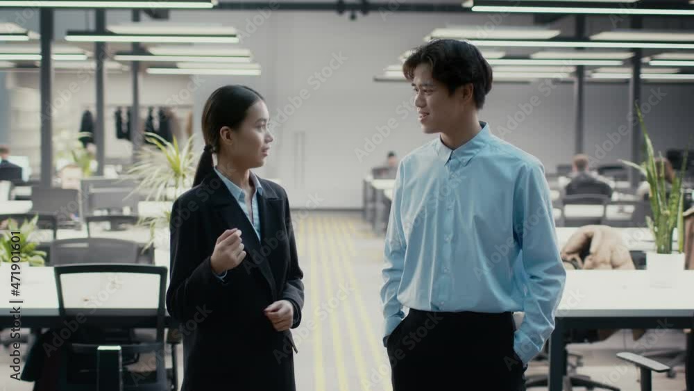 Two Chinese Colleagues Talking Standing In Modern Office Indoors Two Chinese Colleagues Talking Standing In Modern Office Indoors