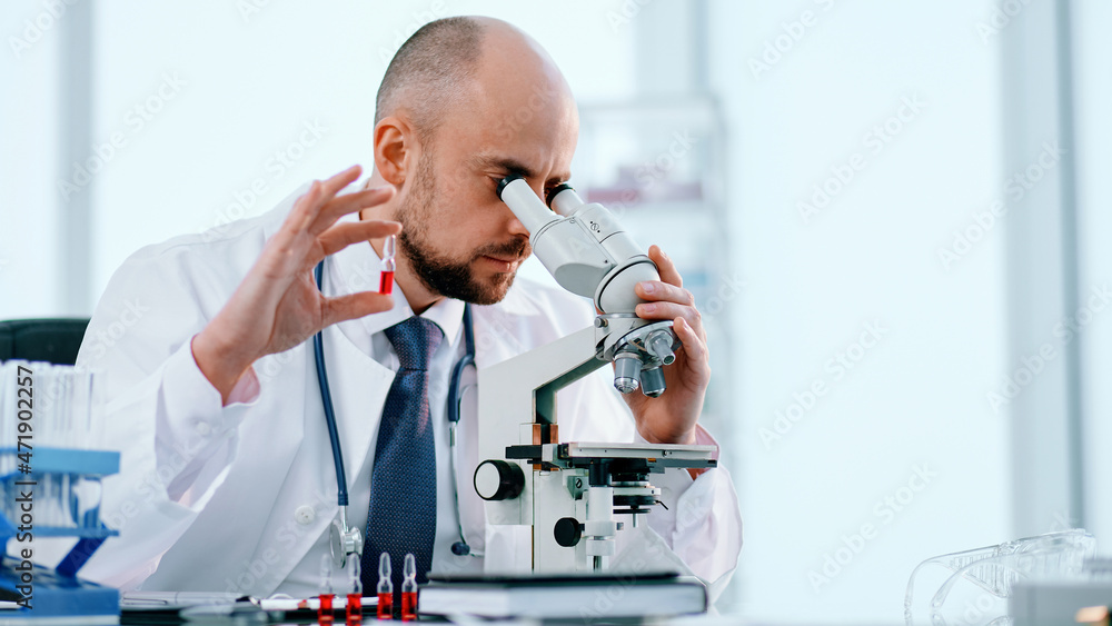 scientist studying vaccine samples through a microscope . scientist studying vaccine samples through a microscope .