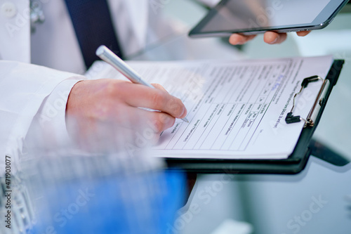 laboratory assistant with a digital tablet filling out a medical form.