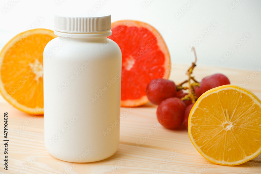 Vitamins. White empty bottle for vitamins on a background of citrus fruit slices. lemon. orange. White background. Blank Medicine bottle Vitamins. White empty bottle for vitamins on a background of citrus fruit slices. lemon. orange. White background. Blank Medicine bottle