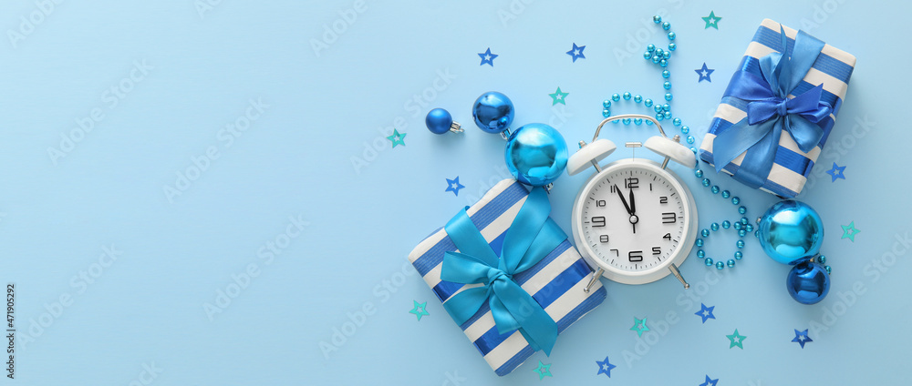 Fototapeta premium Alarm clock with gifts and Christmas decorations on blue background with space for text