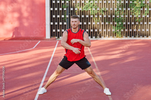 athletic man in red jersey on the sports ground exercise